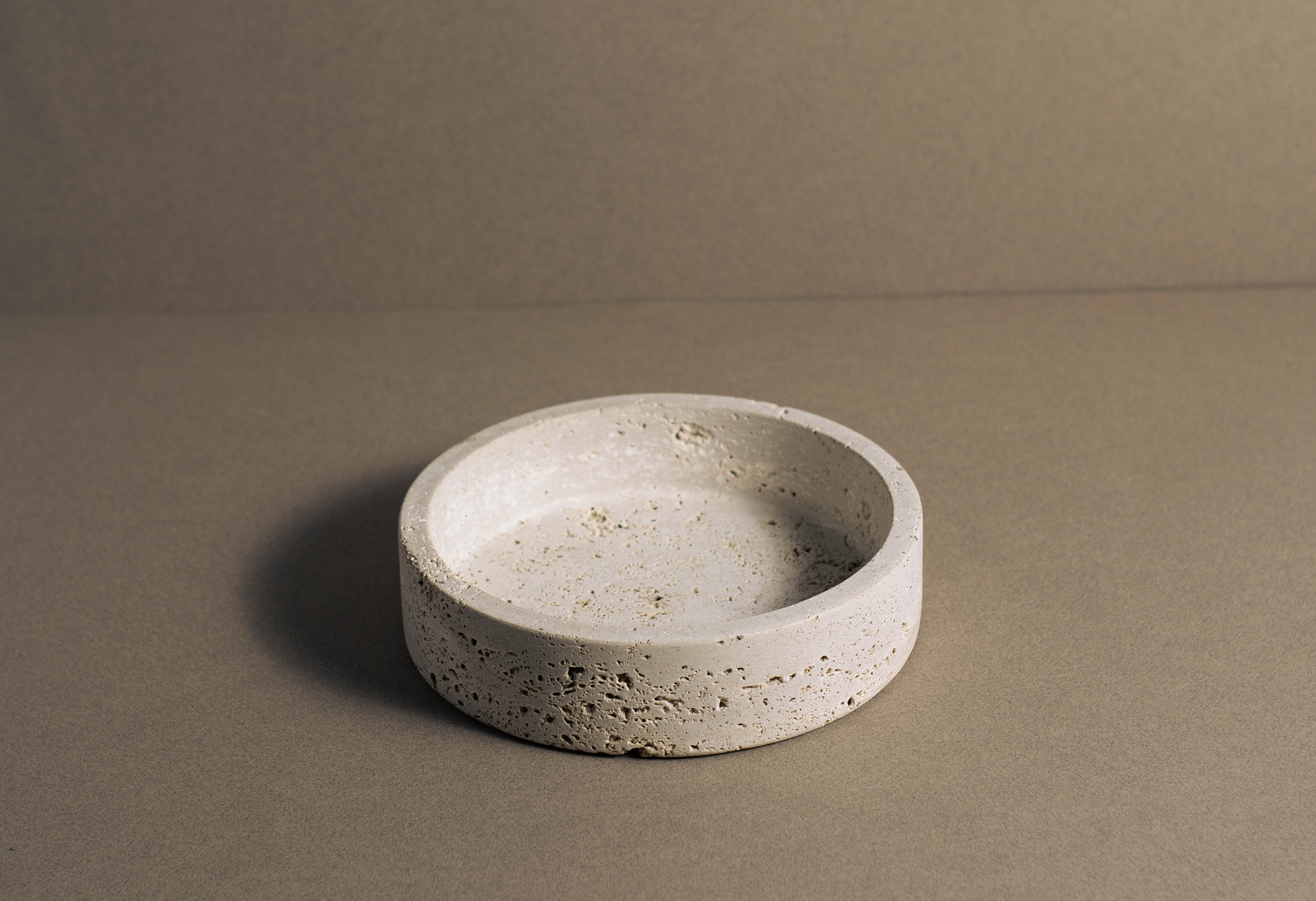 "Round travertine bowl with smooth polished surface and natural veining."