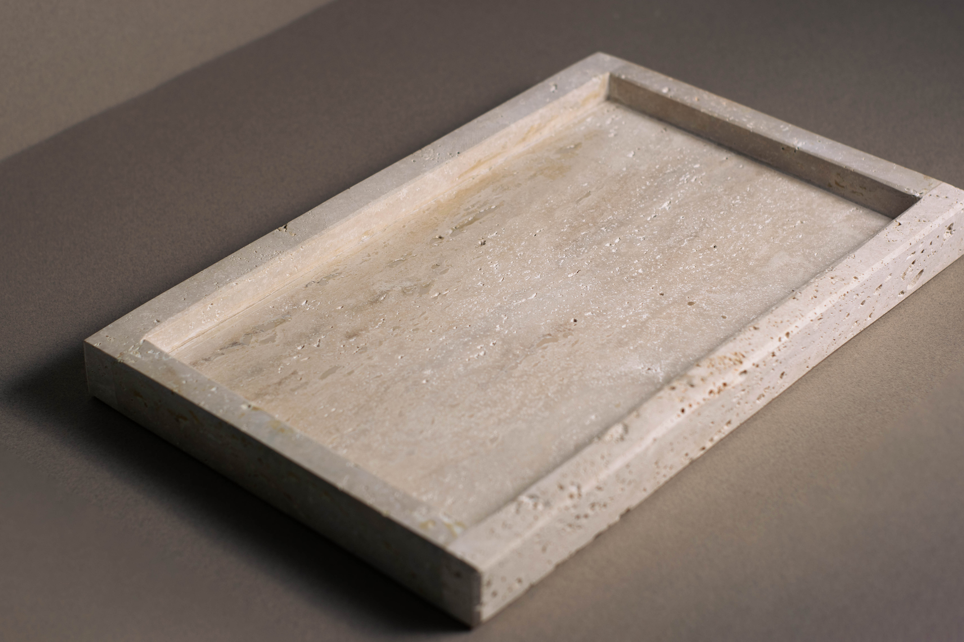 Oblong travertine tray showcasing warm earthy tones and unique veining on a dining table.