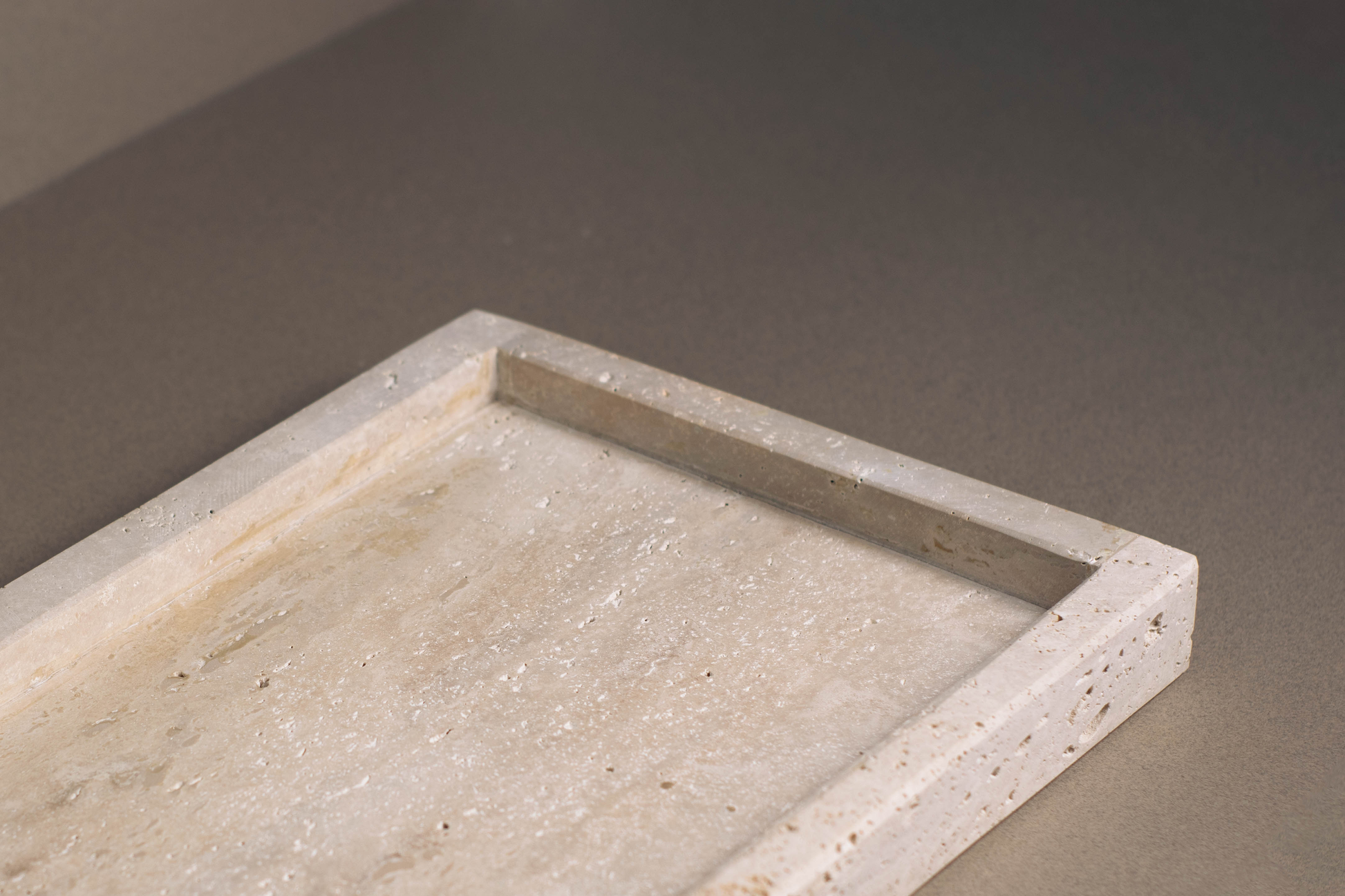 Versatile oblong tray in high-quality travertine used for organizing decorative items on a shelf.