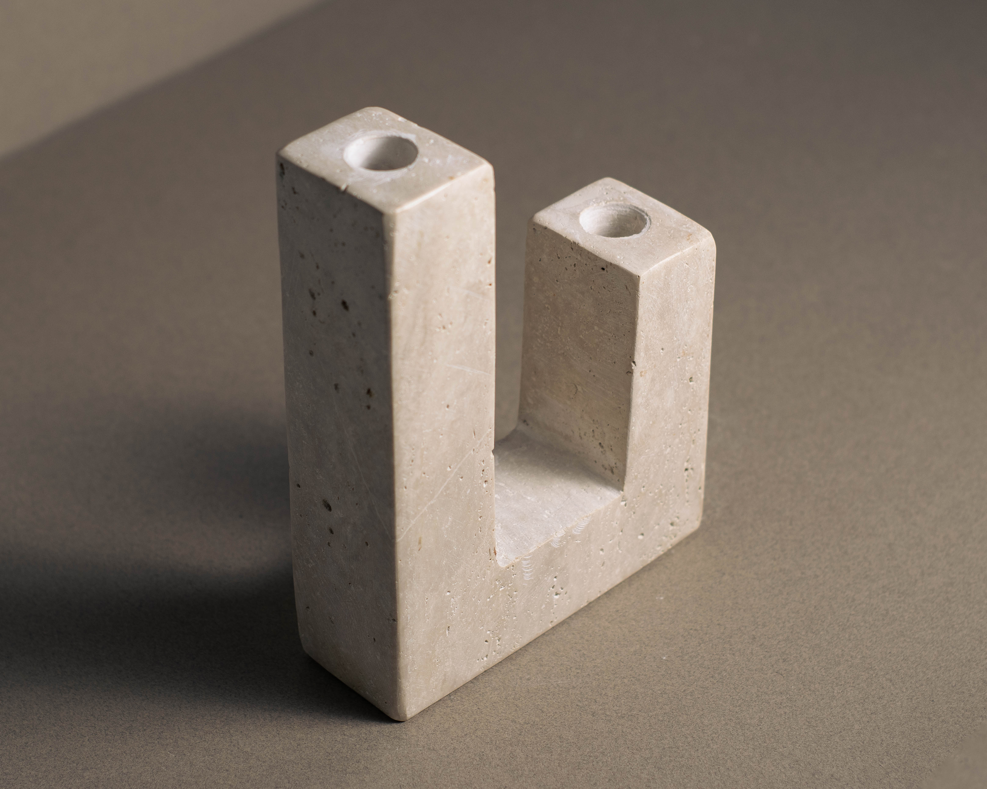 Handcrafted L-shaped candle holder in travertine, highlighting its natural beauty and texture.