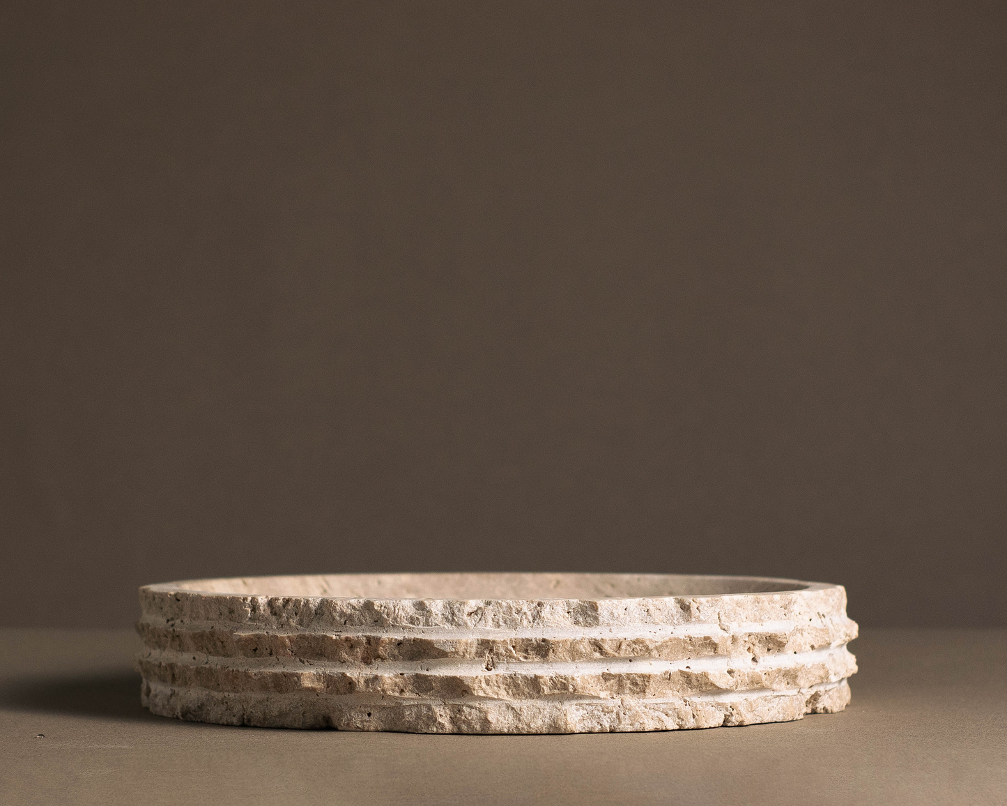 Eclipse travertine bowl displaying its smooth, earthy tones in a modern setting.
