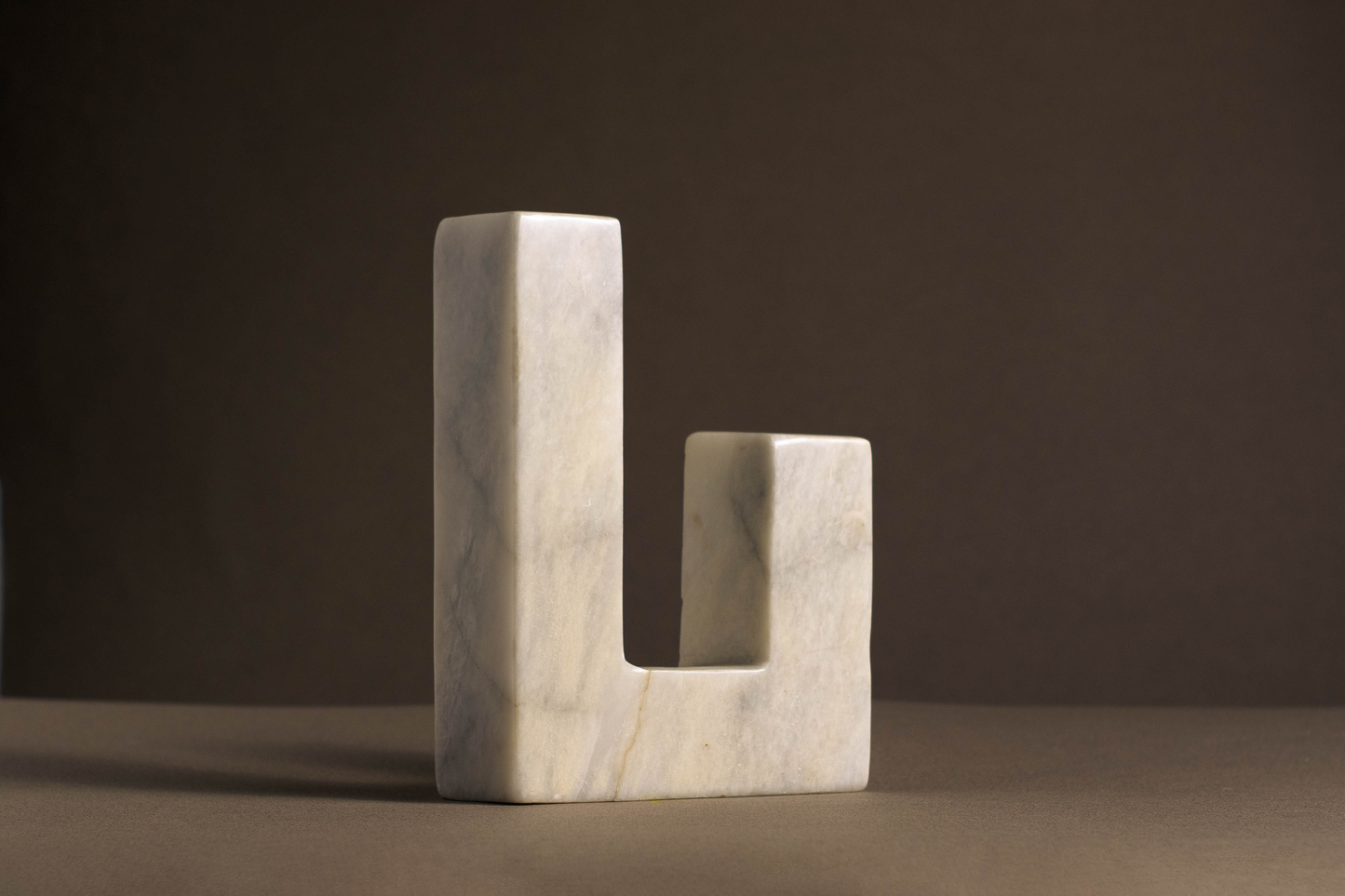 Unique L-shaped candle holder in white marble highlighting its natural beauty and texture.

