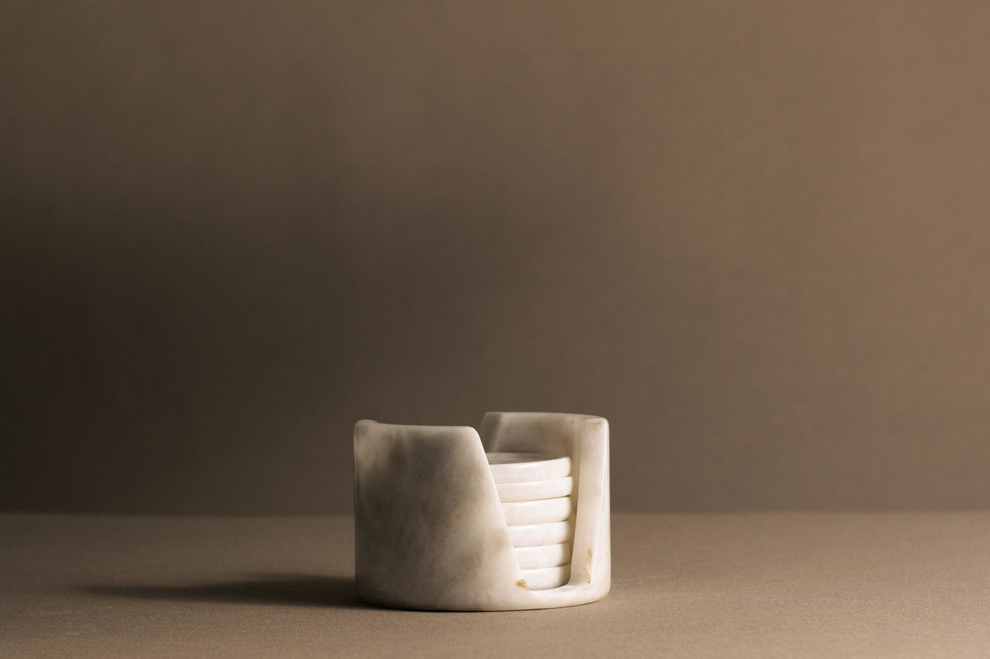 Murmor coasters with holder in white marble elegantly displayed on a dining table.