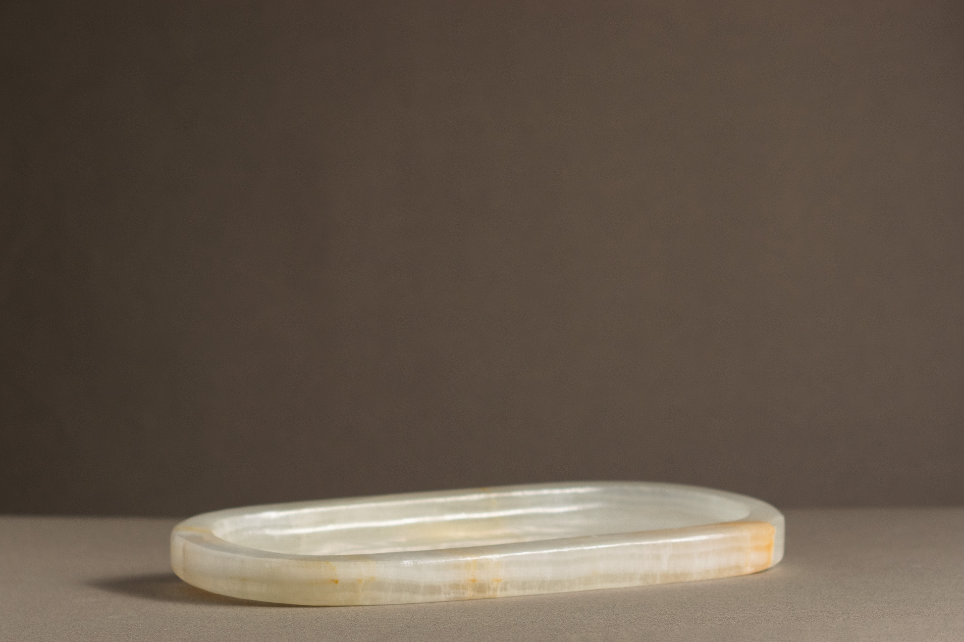 Elegant oval Aura tray in white onyx, featuring a smooth, polished surface and unique veining for stylish home decor.