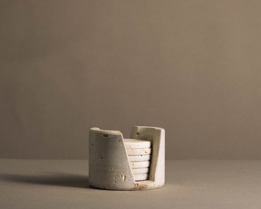 Murmor coasters with holder in travertine elegantly displayed on a dining table.